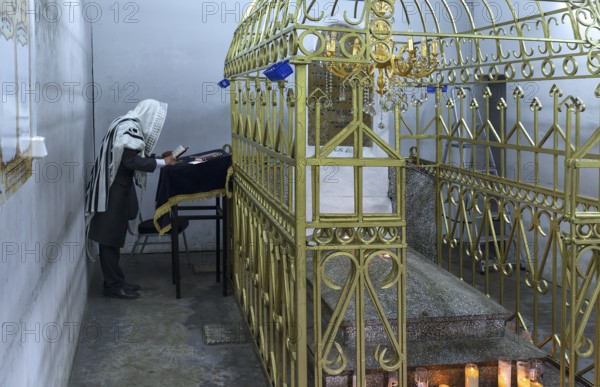 Orthodox Jew praying at the grave of Hasidic Rabbi Elimelech in Lezajsk Jewish Cemetery, Poland