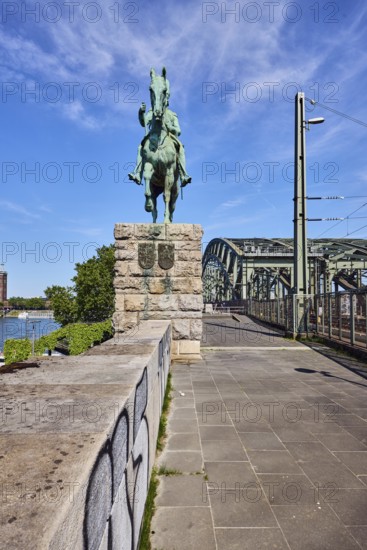 Equestrian statue of Emperor Frederick III, sandstone wall, Hohenzollern bridge, arched bridge, steel arches, trees, blue sky, cirrus clouds, Cologne, district-free city, North Rhine-Westphalia, Germany