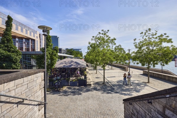 Staircase, natural stone wall, waterfront, Rhine river, commercial building, modern architecture, lantern, city trees, pedestrians as a secondary motif, blue sky, cirrus clouds, cirrostratus clouds, Kennedy embankment, Cologne, district-free city, North Rhine-Westphalia, Germany