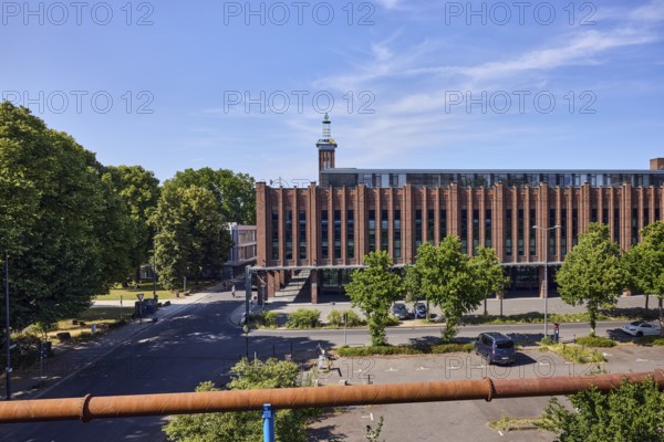 Rheinhallen exhibition halls, brick buildings, aboveground district heating pipeline, parking lot with cars, trees, blue sky, cirrus clouds, Kennedy shore, Charles-de-Gaulle-Platz, Cologne, district-free city, North Rhine-Westphalia, Germany