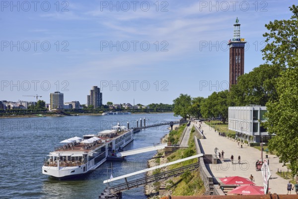 Rhine river, brick architecture, exhibition tower, general architecture, high-rise buildings, waterfront, river cruise ship Viking Einar, Viking Cruises, dock, duckdalben, gangway, quay, quay wall, pedestrian as accessories, lawn, trees, bird's-eye view, blue sky, cirrus clouds, Kennedy shore, Cologne, district-free city, North Rhine-Westphalia, Germany