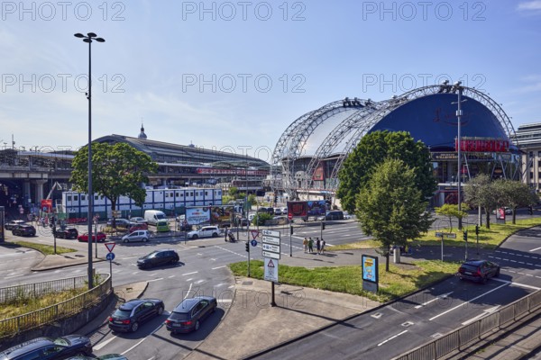 Large tent Musical Dome, general architecture, lantern, main station, roads, lanes, central island, pedestrian crossing, vehicles, parking lot, lawn, trees, elevated perspective, side light, blue sky, cloudless, federal road B51, Konrad-Adenauer-Ufer intersection with Trankgasse, Cologne, district-free city, North Rhine-Westphalia, Germany