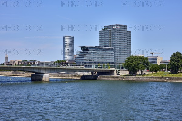 Rhine river, KölnTriangle and MaxCologne skyscrapers, Lanxess, corporate headquarters, car bridge and footbridge Deutzer Brücke, trees, water surface with small waves, blue sky, cloudless, Cologne, district-free city, North Rhine-Westphalia, Germany