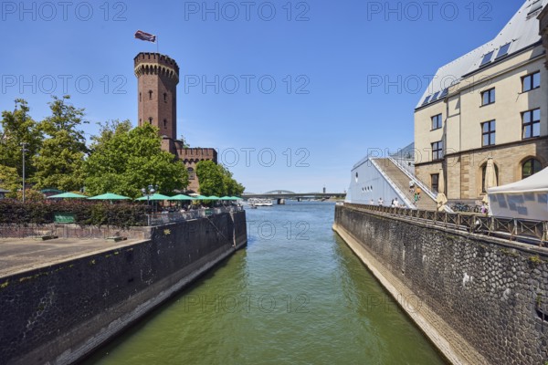 Rhine river, historic port, Rheinauhafen, quay wall, defense tower, Malakoff tower, building, outdoor area of a restaurant, trees, blue sky, cloudless, Cologne, district-free city, North Rhine-Westphalia, Germany