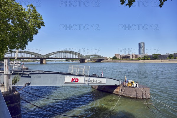Pier, gangway, Cologne-Düsseldorfer Deutsche Rheinschiffahrt GmbH, Rhine river, MaxCologne high-rise building, Hohenzollern bridge, arched bridge, steel arches, general architecture, wharf, branches, trees, water surface with small waves, blue sky, cloudless, Leystapelwerft, Cologne, district-free city, North Rhine-Westphalia, Germany