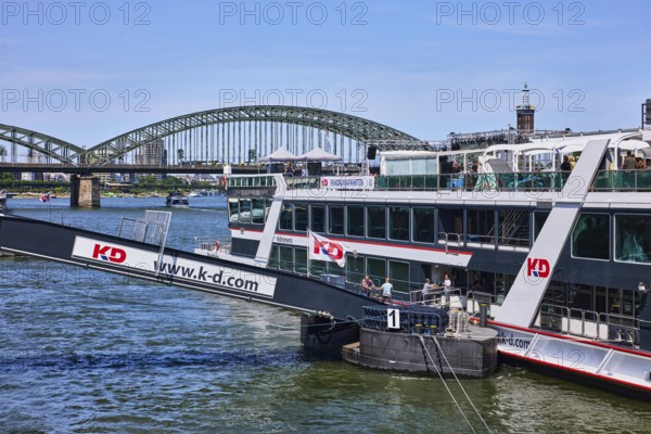 Rhine river, excursion boat, gangway, Cologne-Düsseldorfer Deutsche Rheinschiffahrt GmbH, bridge, Hohenzollern bridge, general architecture, trees, blue sky, cloudless, Leystapelwerft, Cologne, district-free city, North Rhine-Westphalia, Germany