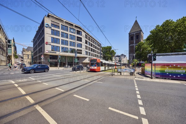 Gürzenich-Quartier, ASTOC Architects and Planners GmbH, commercial building, modern architecture, general development, church tower of Klein St. Martin, traffic light intersection, sidewalk, bicycle path, cars, road markings lanes and cycle path, tram stop, overhead lines, catenary masts, tram tracks, tram, tram crossing for pedestrians, trees, blue sky, cloudless, Kleine Sandkaul intersection, Augustinerstraße und Pipinstraße, Cologne, district-free city, North Rhine-Westphalia, Germany