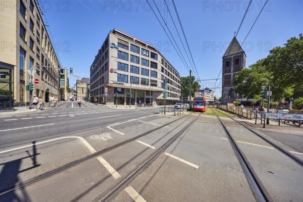 Gürzenich-Quartier, ASTOC Architects and Planners GmbH, commercial building, modern architecture, general development, church tower of Klein St. Martin, traffic light intersection, sidewalk, pedestrian crossing, bicycle path, tram stop, overhead lines, catenary masts, tram tracks, tram crossing for pedestrians, pedestrians as a secondary motif, road markings lanes and cycle path, blue sky, cloudless, Kleine Sandkau intersection l, Augustinerstraße und Pipinstraße, Cologne, district-free city, North Rhine-Westphalia, Germany