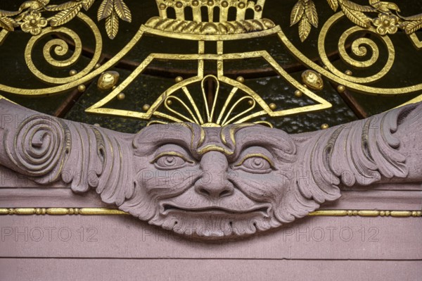A stone face surrounded by ornaments and decorations, detailed view of the main portal of the 120-year-old historic Hegau-Gymnasium in Singen am Hohentwiel, stonemasonry, art nouveau blacksmithing, district of Constance, Baden-Württemberg, Germany