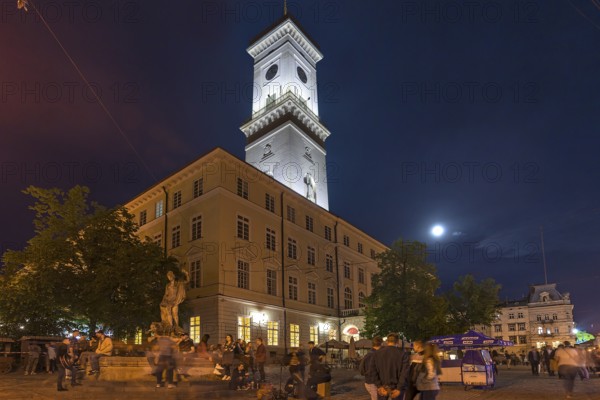 Evening atmosphere in the old town district with illuminated town hall tower, Lviv, Ukraine
