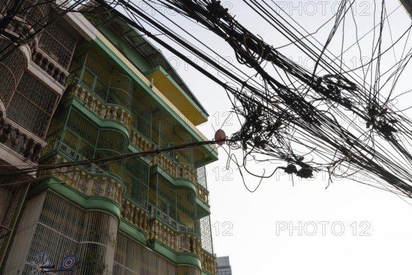 Bangkok, Thailand. March 4th 2025. A tangled mess of cables and wires used for phone and internet connections hanging from a pole in the street in central Bangkok, Thailand