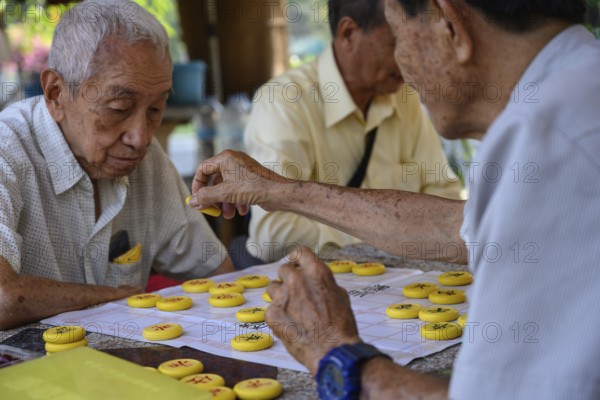 Bangkok, Thailand. March 4th 2025. Old men play Chinese board games on a Sunday morning in Lumphini Park, Bangkok