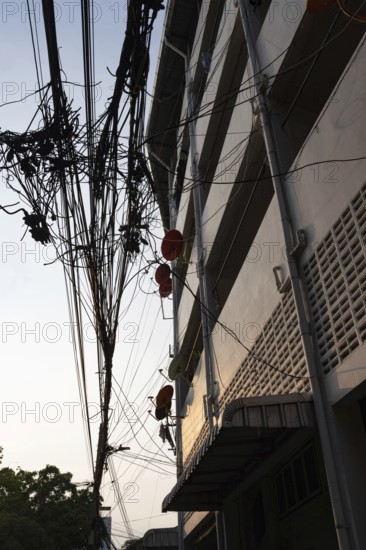 Bangkok, Thailand. March 4th 2025. A tangled mess of cables and wires used for phone and internet connections hanging from a pole in the street in central Bangkok, Thailand