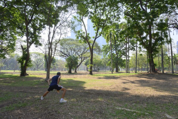 Bangkok, Thailand. March 4th 2025. A local man does some warm up stretches and exercises to keep fit in Lumphini Park, Bangkok