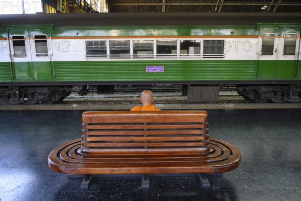 A Buddhist monks waits for his train on the platform at Hua Lamphong Railway Station, Bangkok, Thailand