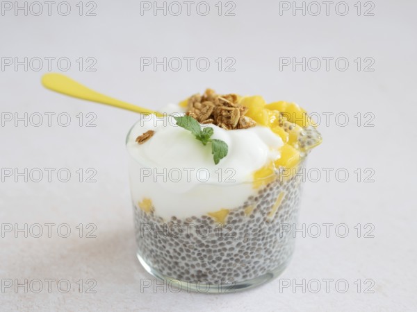 Chia seed pudding layered with mango, yogurt, and granola, topped with fresh mint