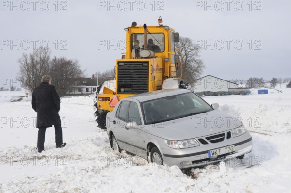 Car stuck in snow gets help from a loader to get free in Skurup municipality, Skåne county, Sweden, Scandinavia