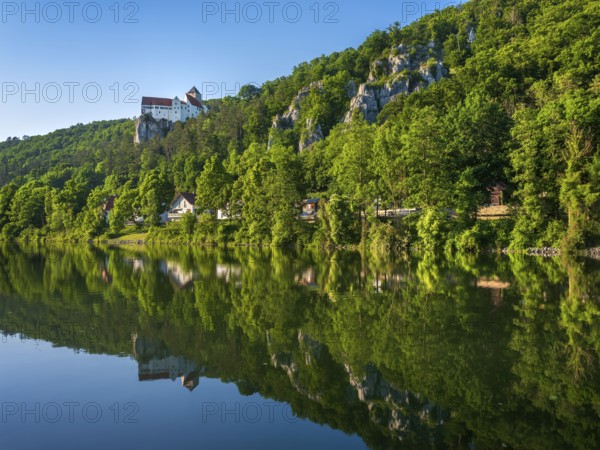 Prunn Castle on steep rock above the Altmühl Valley in the evening light, reflection in the river Altmühl as part of the Main-Danube Canal, near Riedenburg, Altmühltal nature park Park, Lower Bavaria, Germany