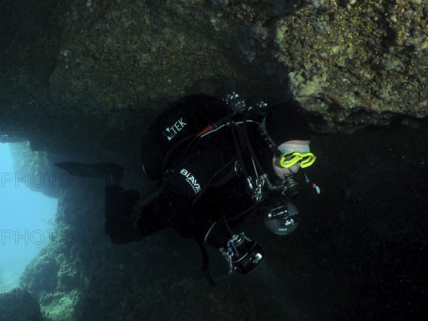 Diver, cave diver, in the dark area of an underwater cave wears diving equipment. Fraskeric dive site, Stoja, Pula, Croatia, Mediterranean Sea