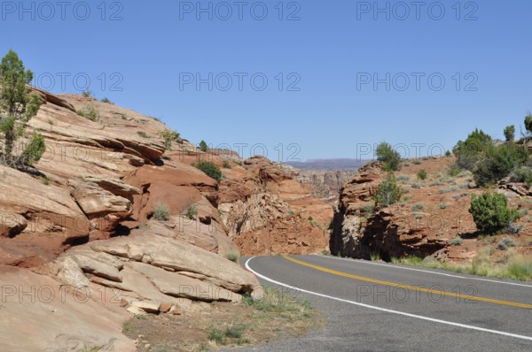 Paved road through red rock landscape under clear blue sky, Grand Staircase Escalante National Monument, Utah, USA