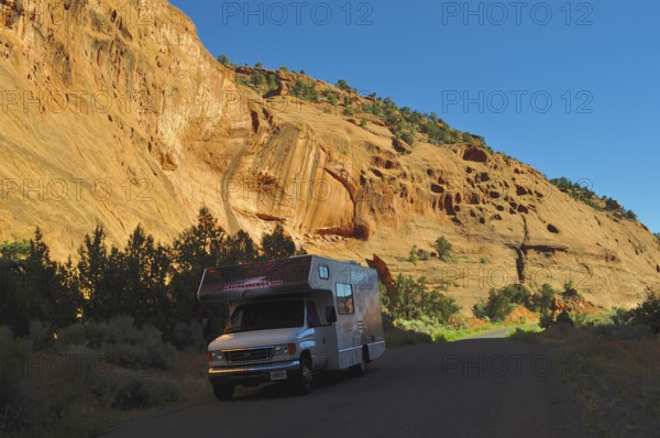 An RV parks on a road in a sunny rocky landscape with deep shade, Grand Staircase Escalante National Monument, Utah, USA