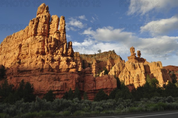 Massive red rock formations in sunlight under a blue sky with clouds, Bryce Canyon National Park, Utah, USA