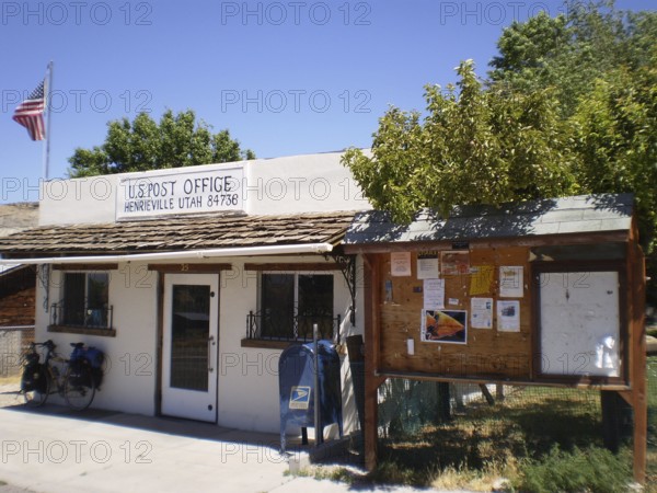 Small post office building with a US flag and attached information board in a quiet village, Henrieville Post Office, Bryce Canyon National Park, Utah, USA