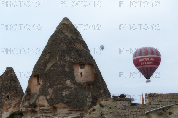 Goreme, Cappadocia, Turkey. October 13th 2018 Hot air balloons rise of traditional cone shaped rock cave houses in Goreme Village, Cappadocia, Central Anatolia, Turkey