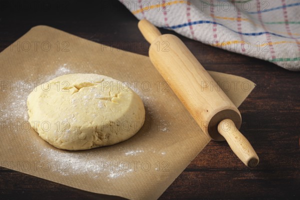 Dough on baking paper with a rolling pin next to it