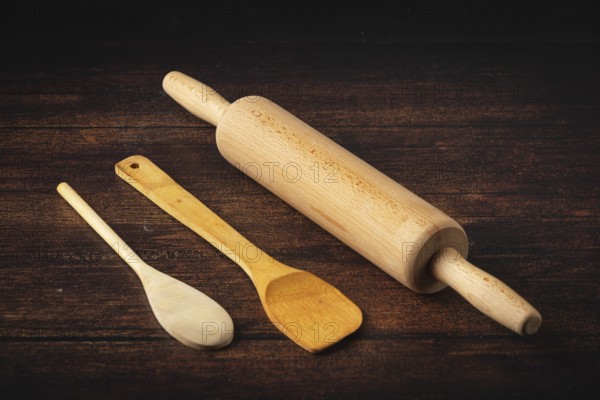 Rolling pin and wooden utensils on a dark wooden table in a rustic atmosphere