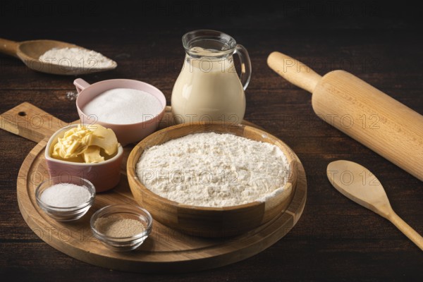 Baking ingredients and utensils such as a rolling pin, bowl of flour, sugar, butter and a pot of milk