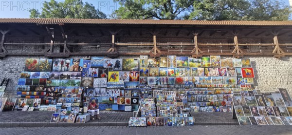 Many colorful paintings hang for sale on a wall, Krakow, Poland