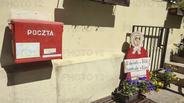 Red mailbox and doll decoration with flowers in sunny surroundings, Masuria, Poland