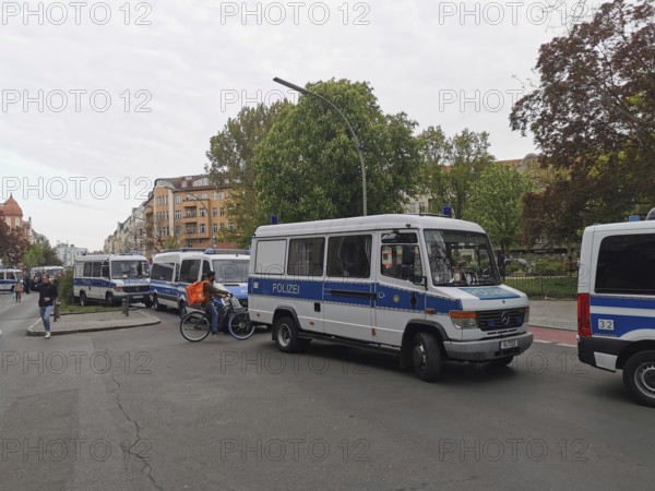 Several police vehicles on a city street, surrounded by buildings and trees, on the sidelines of the Labor Day demonstration in Berlin