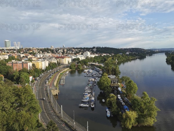 View from above of a district of Prague, on a river with boats, surrounded by green trees and cloudy sky, Prague, Czech Republic