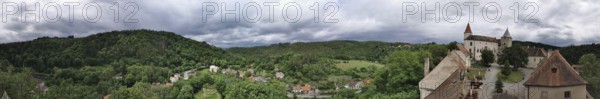 Panoramic view of a hilly landscape with a castle complex and thick greenery under cloudy sky, Krivoklat, Czech Republic