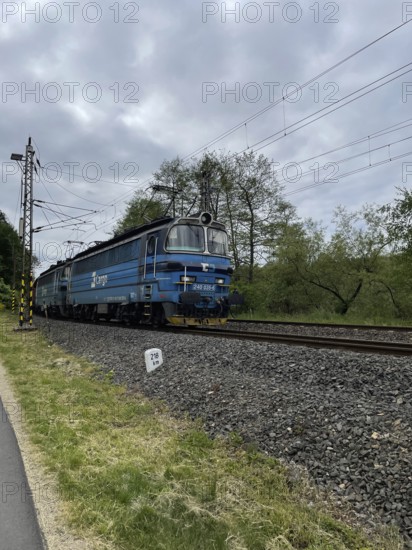 Blue train on tracks in a rural area under cloudy sky, Czech Republic