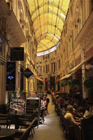 Romania, capital Bucharest, Bucuresti, restaurants and cafes in Passage Macca-Villacrosse, Pasajul Macca-Vilacrosse, an arcade street covered with yellow glass in the center of the city