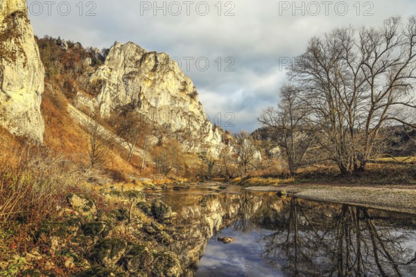 An autumn landscape with a river reflecting the surrounding rocks and trees, under a cloudy sky, Upper Danube nature park Park, Fridingen, Tuttlingen district, Baden-Württemberg, Germany