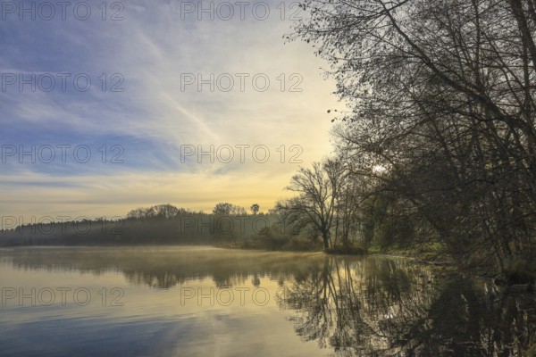 Picturesque landscape with calm lake, trees and gentle sunrise in fog, Schwackenreuter-Baggerseen-Rübelisbach nature reserve, Mühlingen, Konstanz district, Baden-Württemberg, Germany