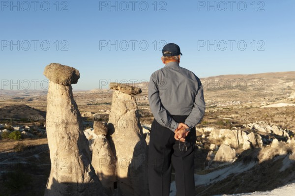 Urgup, Cappadocia, Turkey. September 18th 2018 A Turkish man enjoys the beautiful view of the Three Graces fairy chimneys, an iconic rock formation, part of Cappadocia national park in Central Turkey