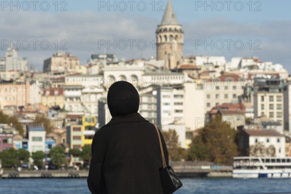 Istanbul, Turkey. November 10th 2022 A Muslim women looks out over the Golden Horn towards the Galata tower on the European side of Istanbul