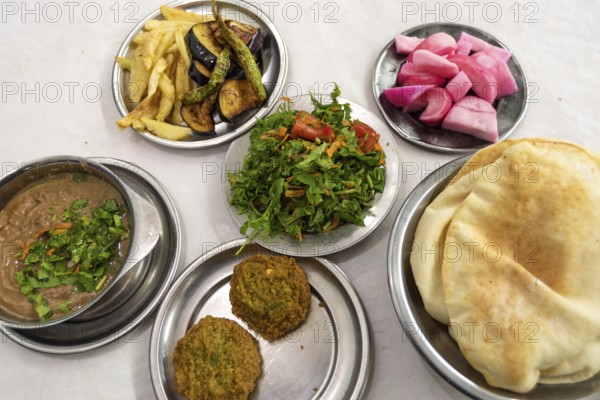 A table prepared with typical Egyptian street food of Fuul and Falafel with Salad, Pickles and Local Bread, healthy and cheap food all over Egypt