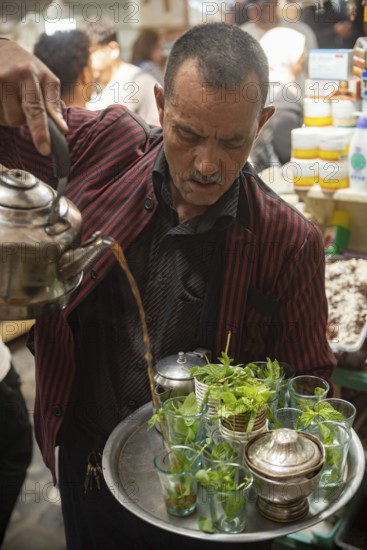 Tunis, Tunisia. 13th May 2024 A Tunisian man pours a glass of tradition mint tea in the busy streets of Tunis Medina, the historical Kasbah is a World Heritage Site in Tunisia on the Mediterranean coast