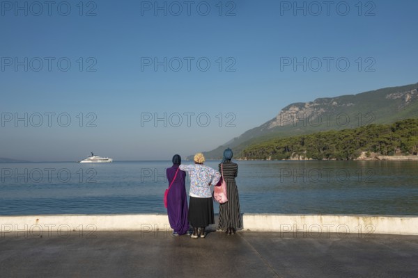 Akyaka, Mugla, Turkey. September 8th 2022 Muslim women visitors to the Turkish seaside town of Akyaka admire the beautiful view and expensive yacht moored in the bay. Turkish coast, Mugla