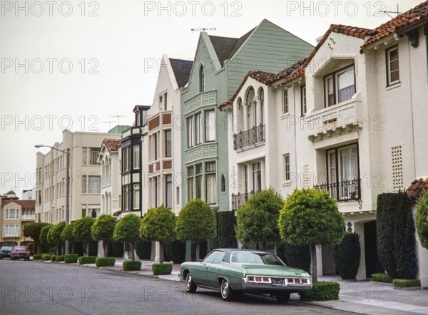 Mediterranean and Spanish Colonial Revival-style row houses stands in the Marina District of San Francisco, captured in 1976. A dark green 1972 Chevrolet Impala
