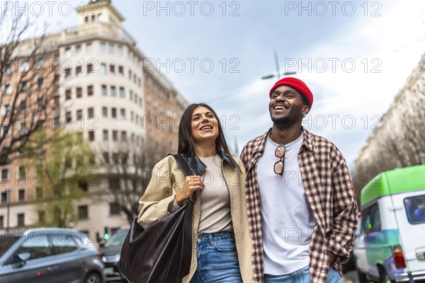 Happy multicultural couple walking together, smiling cheerfully while exploring the urban environment on a casual day, sharing a moment of connection and joy