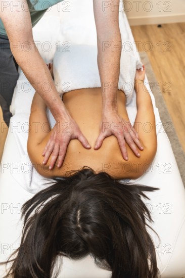 Masseuse performing deep tissue therapy on young womans back, focusing on muscles and shoulders for pain relief, relaxation and holistic well being in a calm spa setting