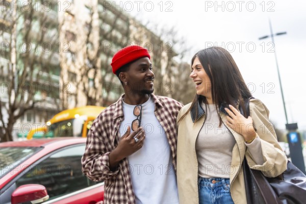 Diverse young couple walking together in an urban setting, enjoying a candid moment and sharing laughter, depicting happiness, a strong relationship, and modern lifestyle
