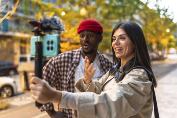 Happy young multiracial couple creating social media content, live streaming, and recording video outdoors on a city street with a smartphone on a gimbal